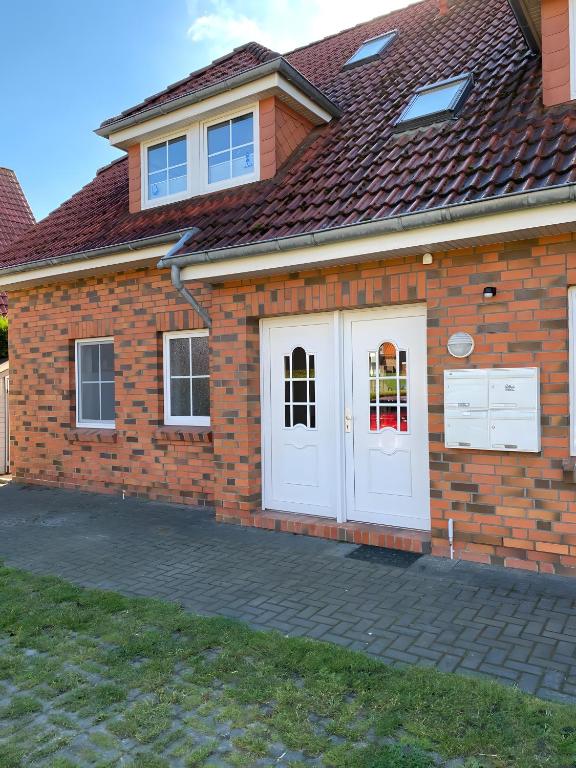 a brick house with a white door at Ferienwohnung Charly in Carolinensiel