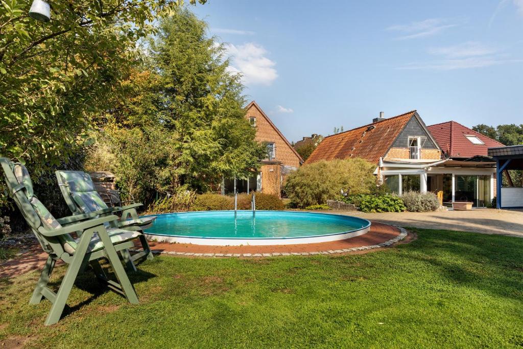 a swimming pool in a yard with a chair at Ferienhaus In Oerrel Mit Pool in Munster
