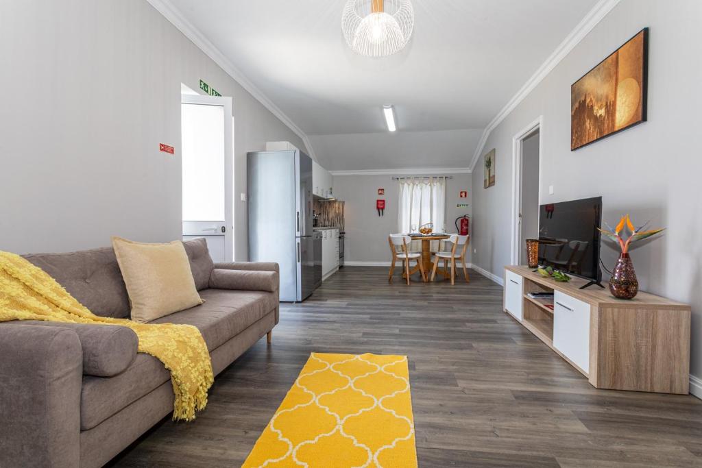 a living room with a couch and a tv and a kitchen at Oásis Fonte Grande in Ponta Delgada