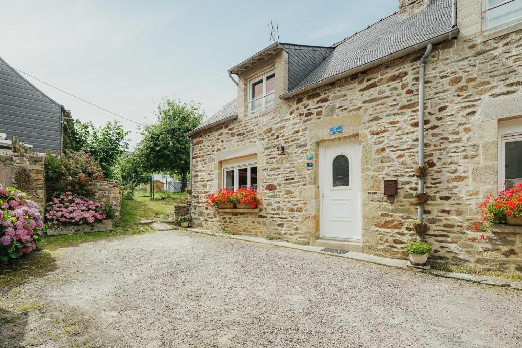a stone house with a white door and flowers at Gite Les Dauphins à Matignon in Matignon