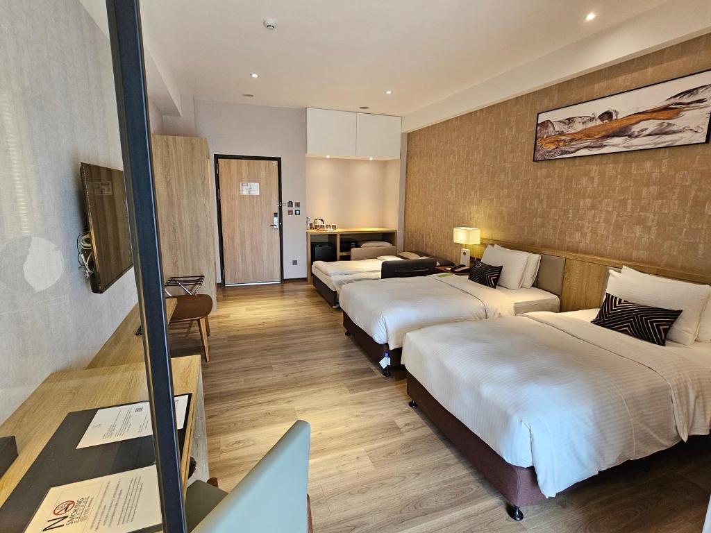 a hotel room with four beds and a desk with a laptop at Joyfultel in Guishan