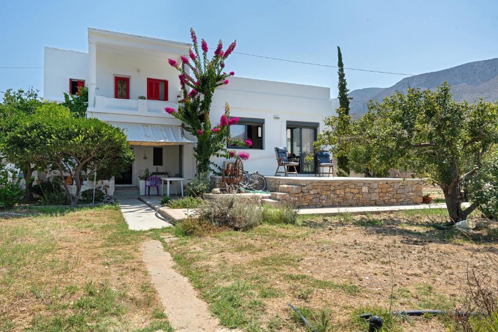 a white house with a yard with trees at Livadi House Amorgos in Aegiali