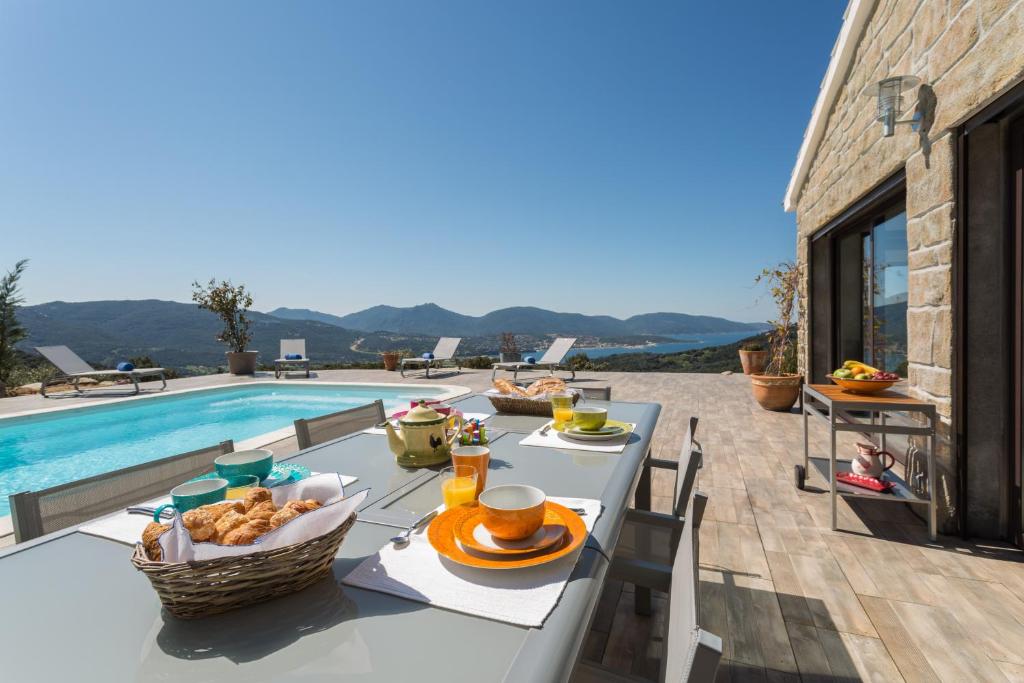 a table with food on it next to a swimming pool at Villa Kalliste in Olmeto