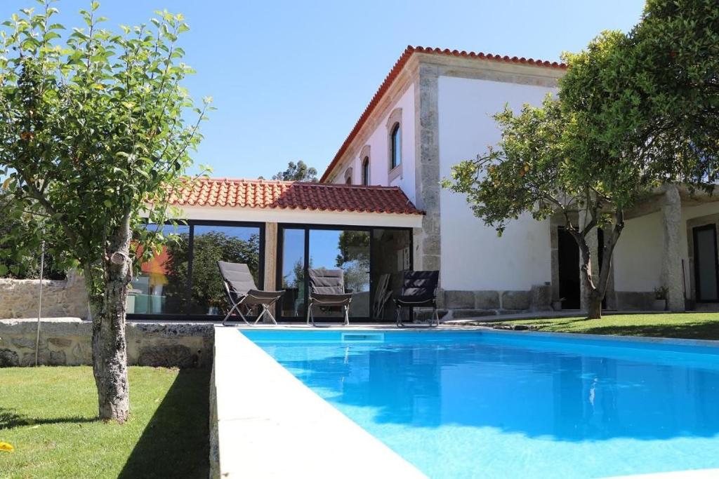 a villa with a swimming pool in front of a house at Casa do Mestre Inteira in Vila de Punhe