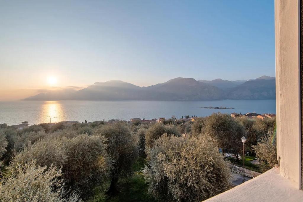 a view of a body of water with the sun setting at Cozy Sommavilla Residence in Brenzone sul Garda