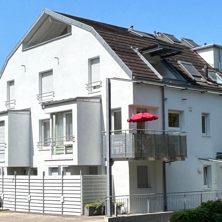 a white building with a red umbrella on a balcony at Ferienwohnung am Neumagen in Staufen im Breisgau