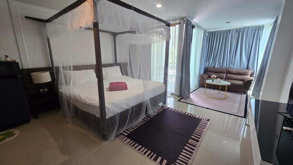 a bedroom with a canopy bed and a couch at joyful theKris 205 in Ban Lum Fuang