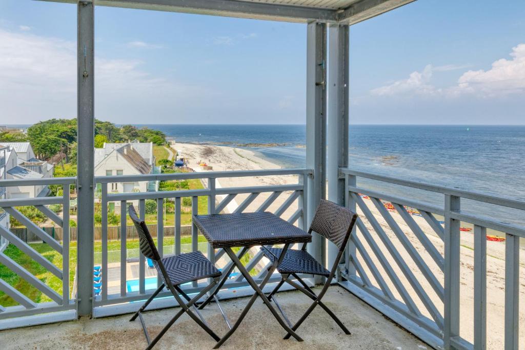 two chairs and a table on a balcony overlooking the ocean at Appartement face mer et Piscine in Le Croisic