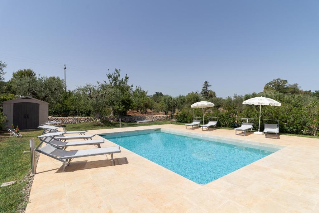 a swimming pool with lounge chairs and umbrellas at Corallo House in Polignano a Mare
