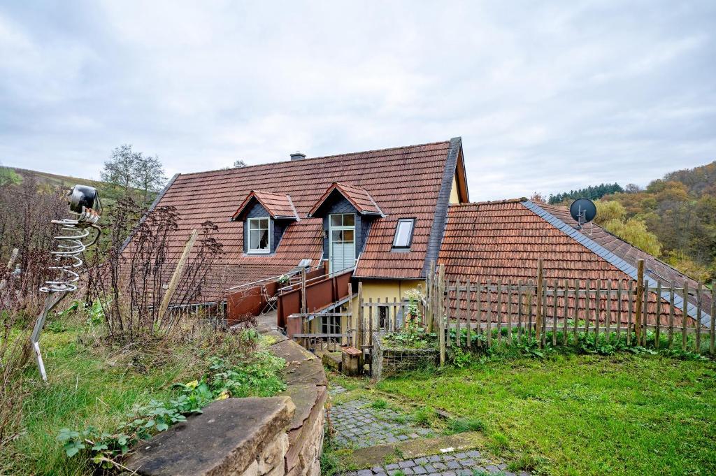 a house with a red roof and a fence at Ferienwohnung Kaffee-Mühle in Sponheim