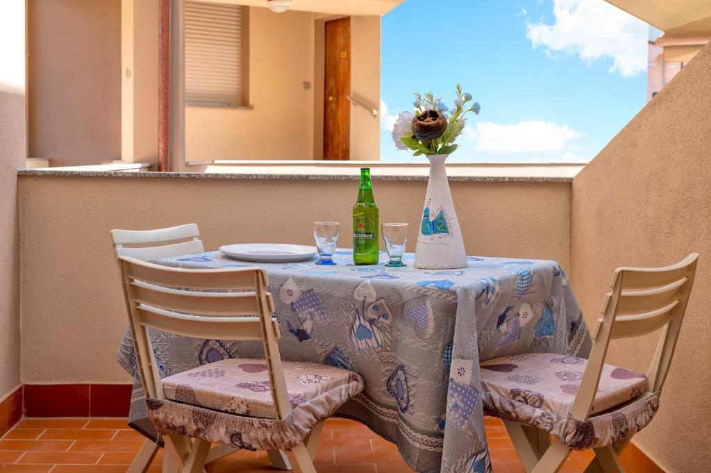 a table with a vase of flowers and a table with chairs at Casa Sara Lu Bagnu in Castelsardo