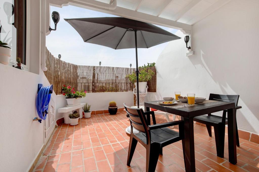 a table with chairs and an umbrella on a patio at Casa Alisios in Costa Calma