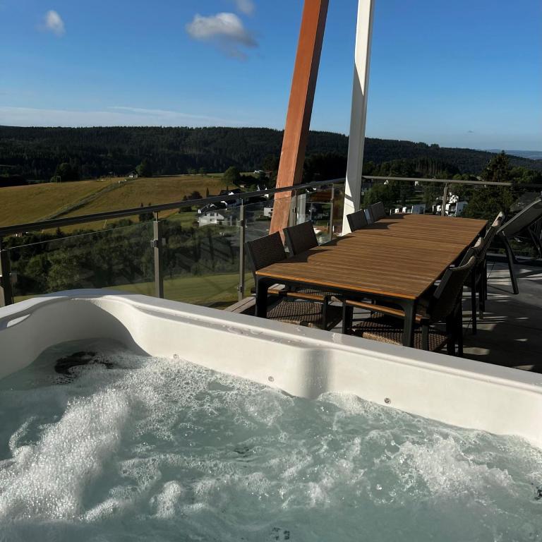a hot tub on the deck of a house with a table at Wellnessappartement Winterberg D4 in Winterberg