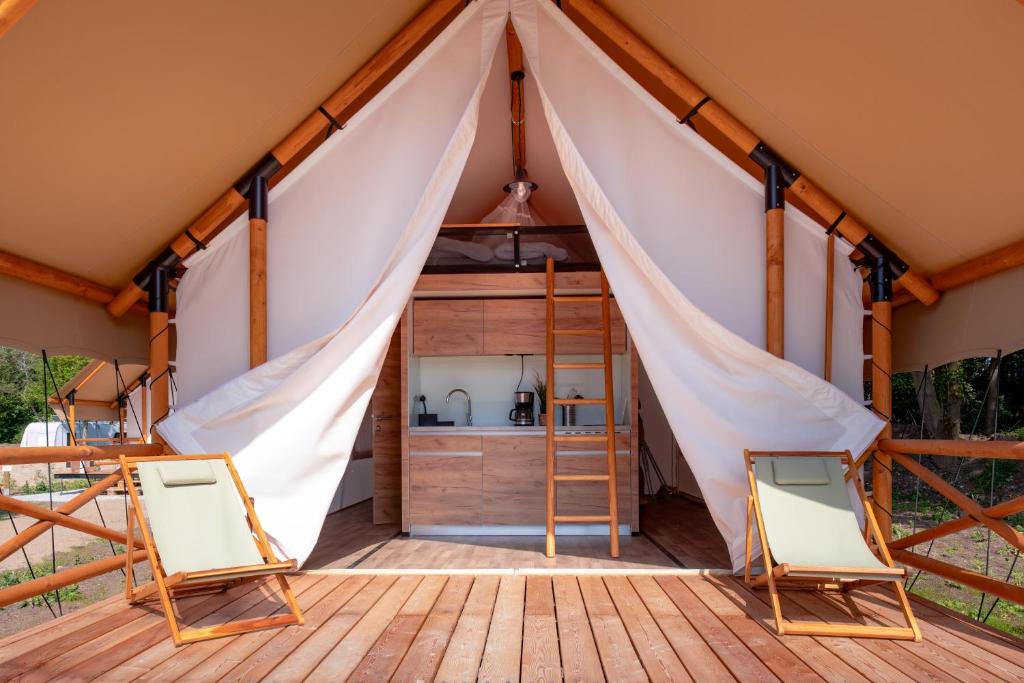 a tent with a kitchen and two chairs on a deck at Safarizelt in Großenbrode