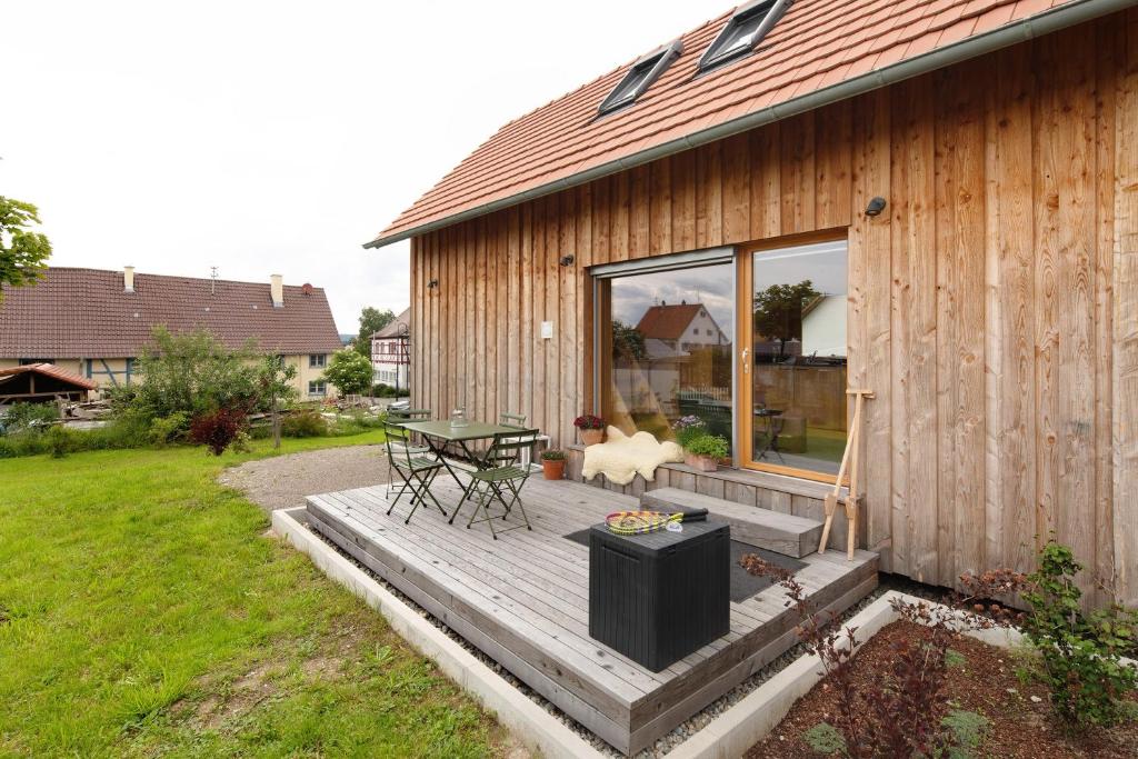 a house with a wooden deck with a table at Tinyhaus am Bussen in Unlingen