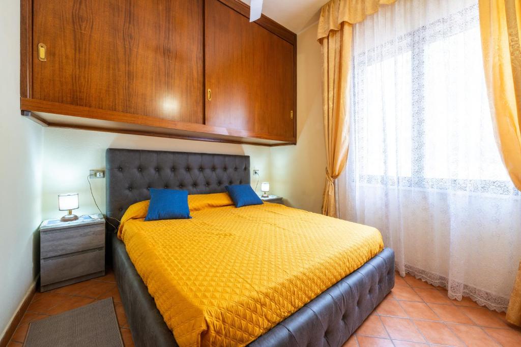 a bedroom with a bed with yellow sheets and blue pillows at Appartamento Pinus in Santa Margherita di Pula