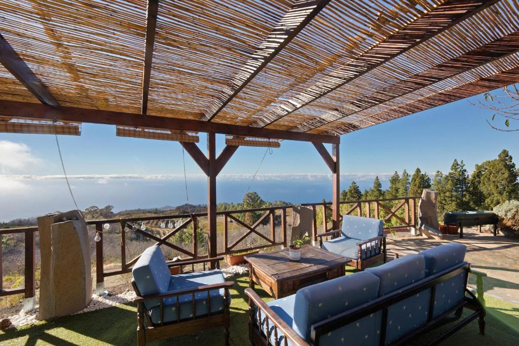 a patio with chairs and a table and a wooden pergola at Media Pipa in Puntagorda
