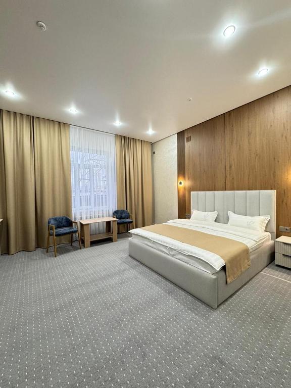 a large bedroom with a large bed and a desk at Essenali in Taraz
