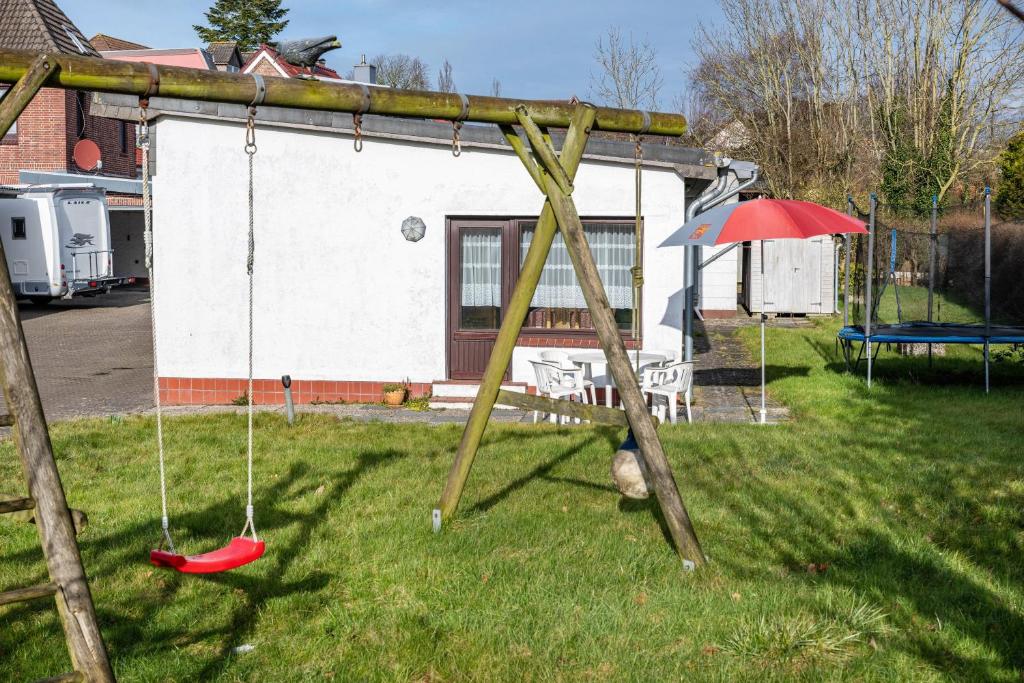 a swing set in a yard with an umbrella at Haus Lahrsen in Wesselburen