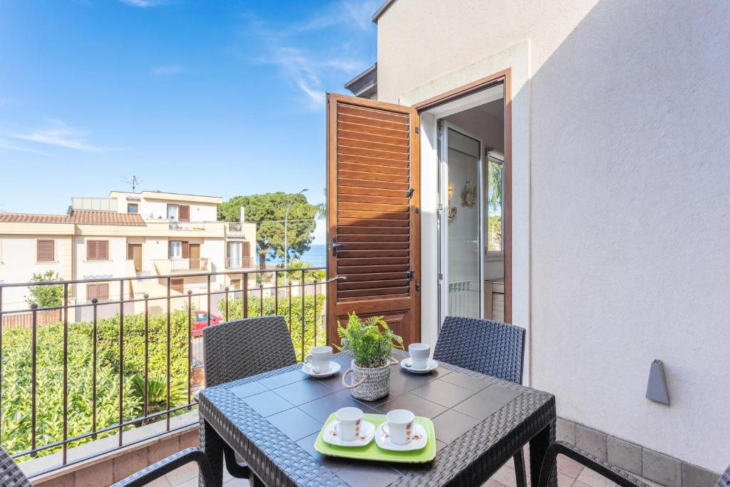 a table with two cups and plates on a balcony at Olimar Home in Santa Flavia