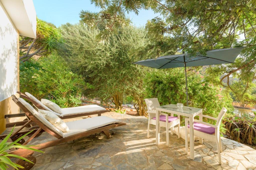 a patio with a table and chairs and an umbrella at Casa Cisne - Selão da Eira in São Miguel