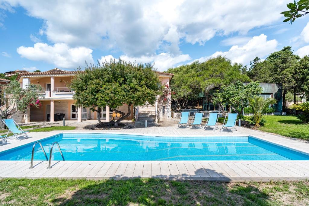 a swimming pool in front of a house with blue lounge chairs at La vela gialla in Cala Liberotto