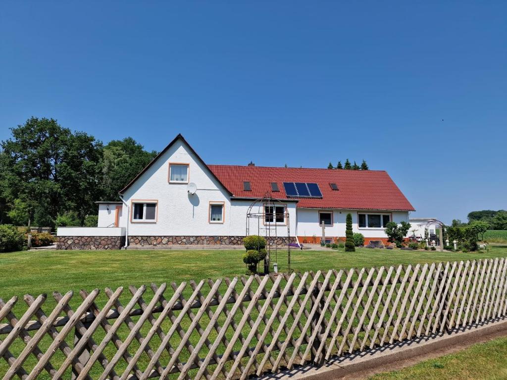 a white house with a red roof behind a wooden fence at Ferienhaus an der Göhrde in Zernien