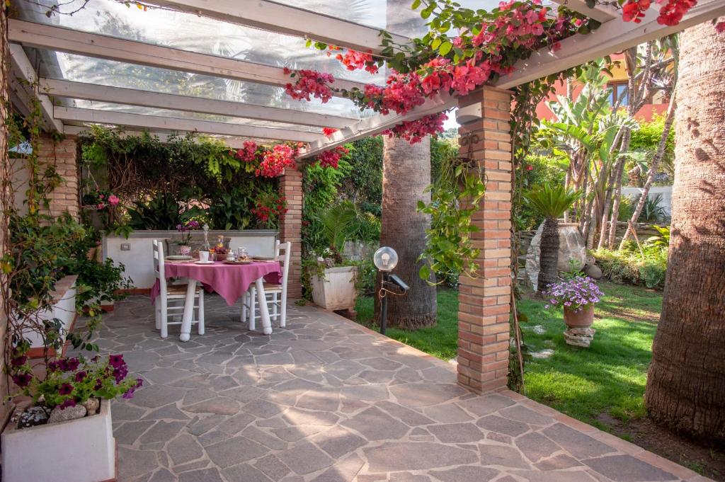a pergola with a table and chairs in a garden at Casa Petunia in Sarroch