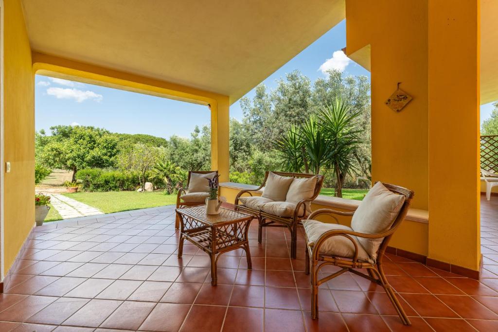 a porch with chairs and a table and a large window at Casa Mameli in Quartucciu