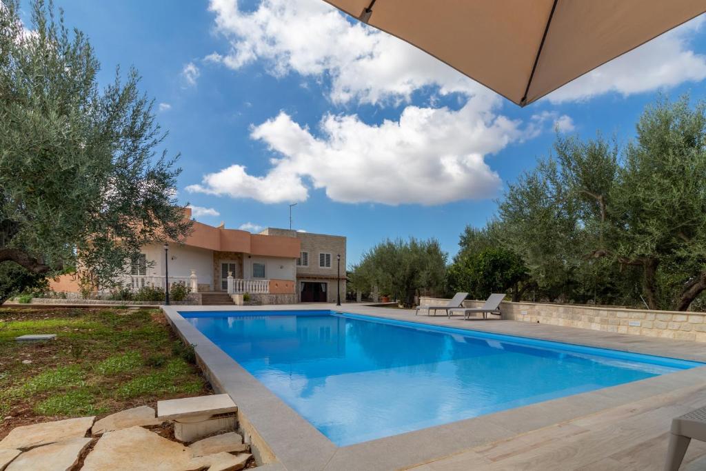 a swimming pool in a yard with an umbrella at Villa Bartolomeo in Modica