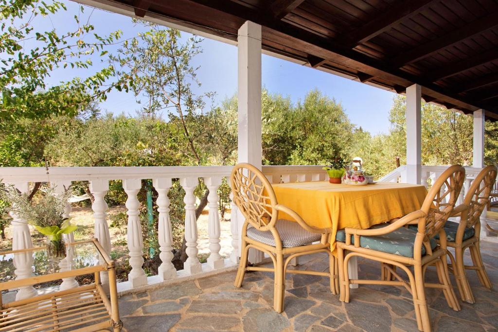 a porch with a yellow table and chairs on it at Areti Orfeas Apartment 5 in Vasilikos