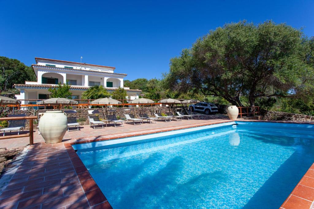 a swimming pool with chairs and umbrellas in front of a building at Villa Mula 1 in Orosei