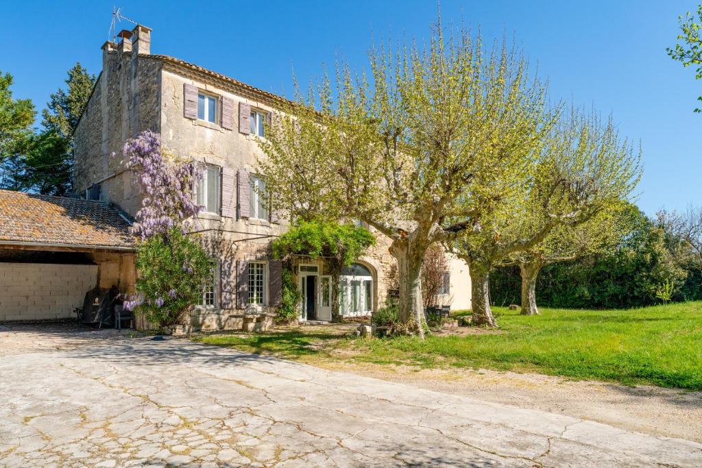 an old stone house with trees in front of it at Le Mas de Kitty - Maison d'hôtes in Saint-Rémy-de-Provence