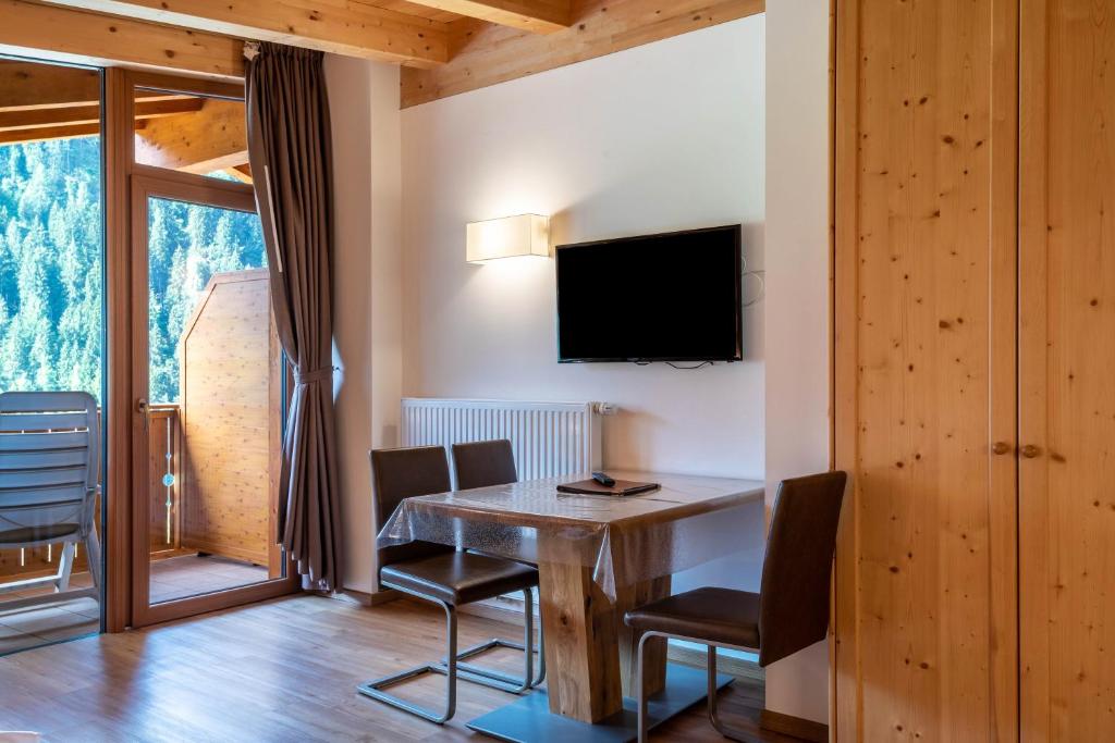 a dining room with a table and chairs and a tv at Hotel Residence Gardena Dolomites in Santa Cristina Gherdëina