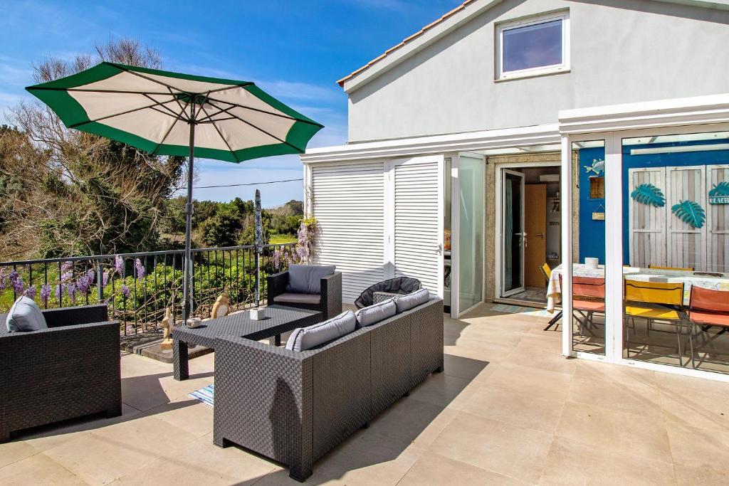 a patio with two couches and an umbrella at Casa Azul in Moledo