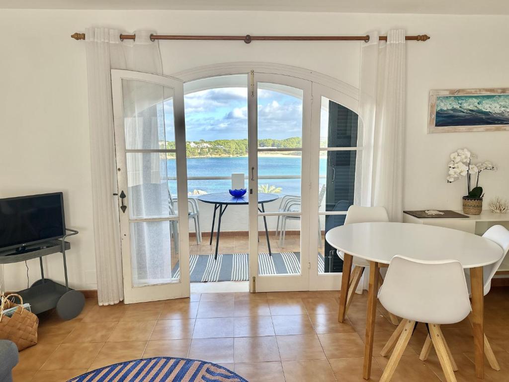 a living room with a table and a view of the ocean at White Sands 4.20 in Arenal d'en Castell