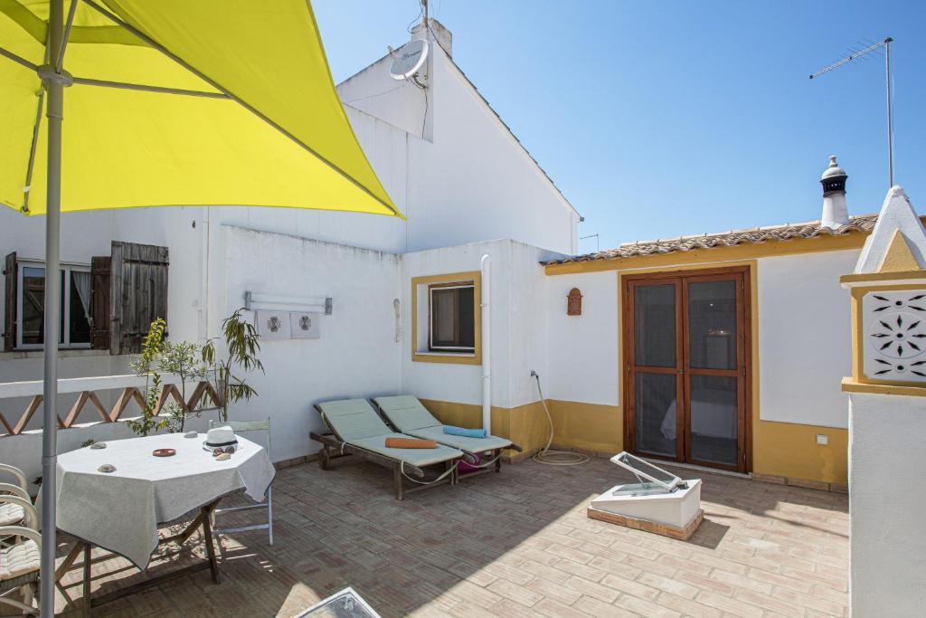 a patio with a table and a yellow umbrella at Casa Milita in Tavira