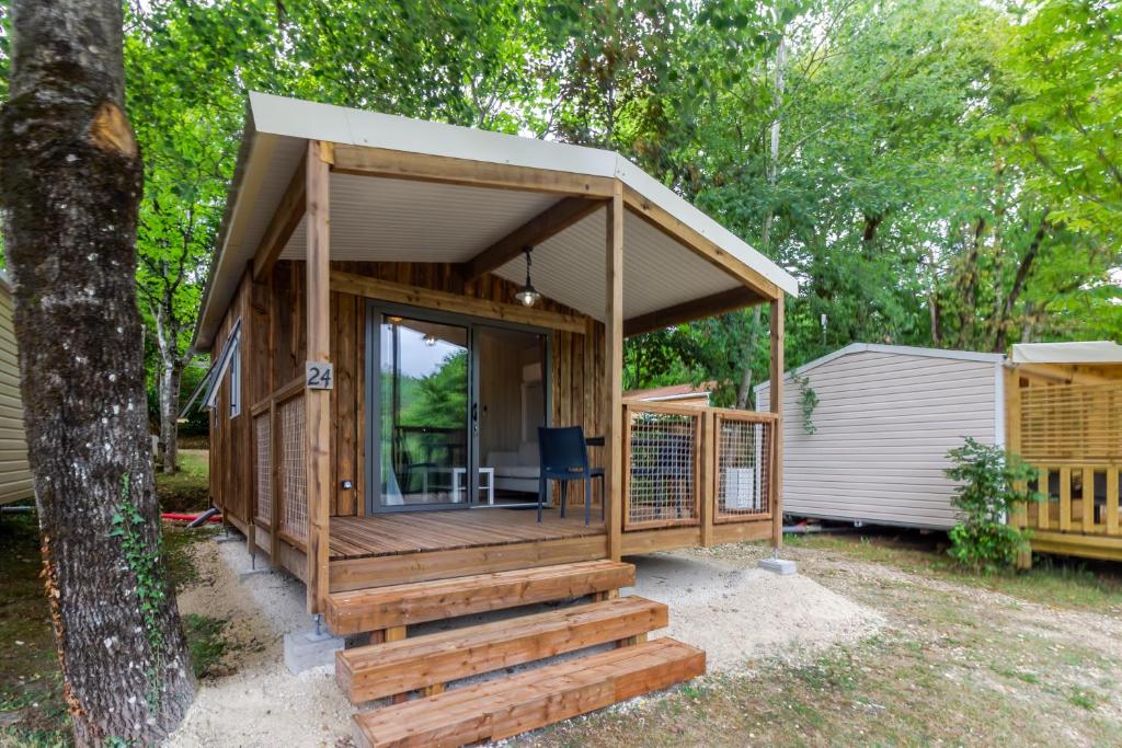 a wooden cabin with a porch and stairs next to a tree at Chalet Franklin 2 personnes in Saint-Martial-de-Nabirat
