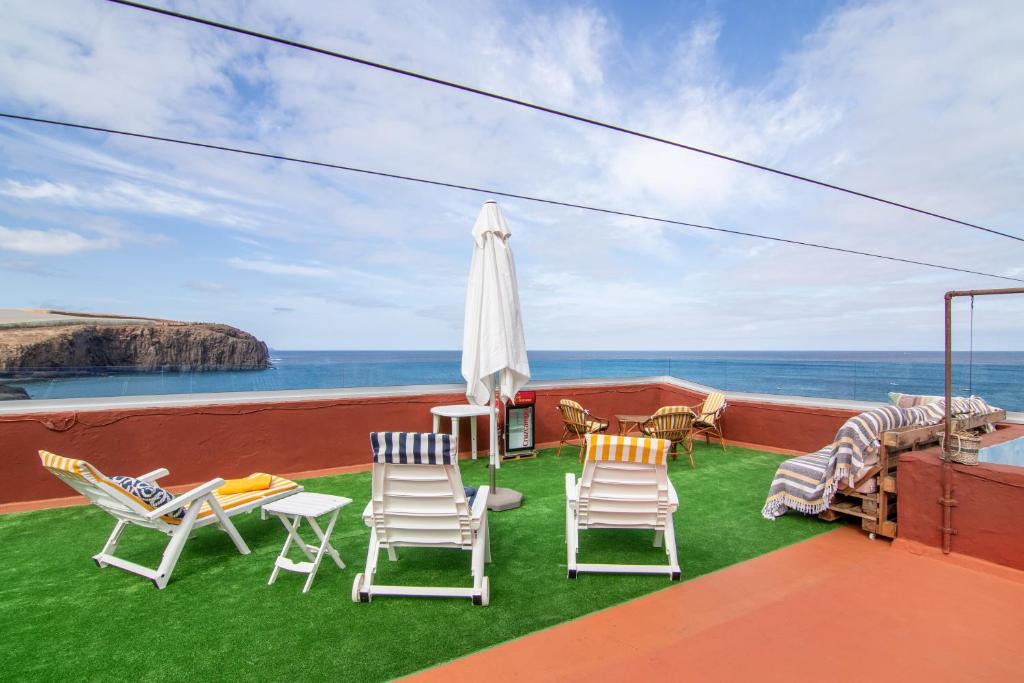 a balcony with chairs and an umbrella and the ocean at Vv Suite Las Velas in Gáldar