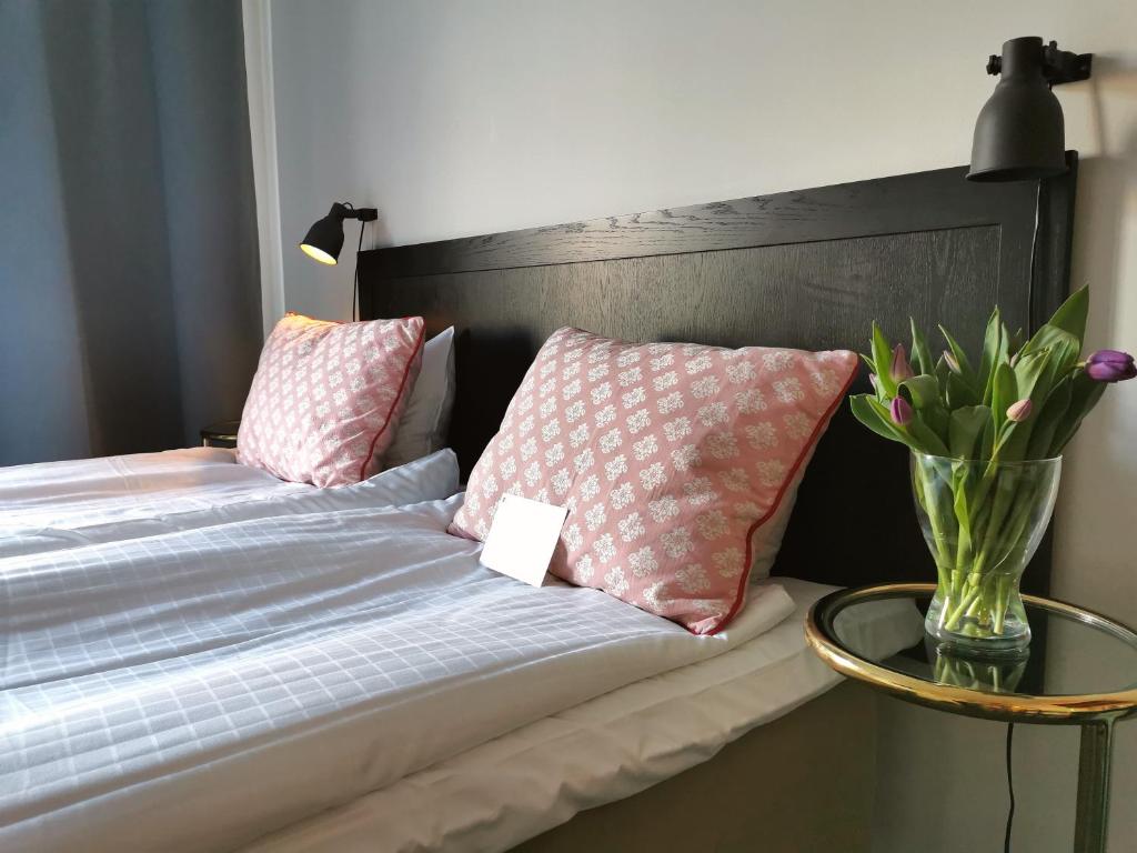 a bed with two pillows and a vase of flowers on it at 2Home Hotel Gävle in Gävle