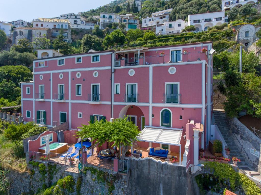 a pink house on the side of a hill at Luxury Villa Soleluna con jacuzzi in Praiano