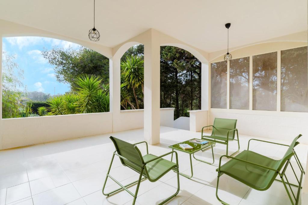 a room with chairs and a table and windows at Villa Camilla a Otranto in Otranto