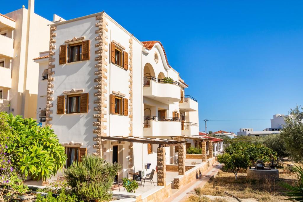 a white building with brown windows and plants at Petra Studios in Karpathos