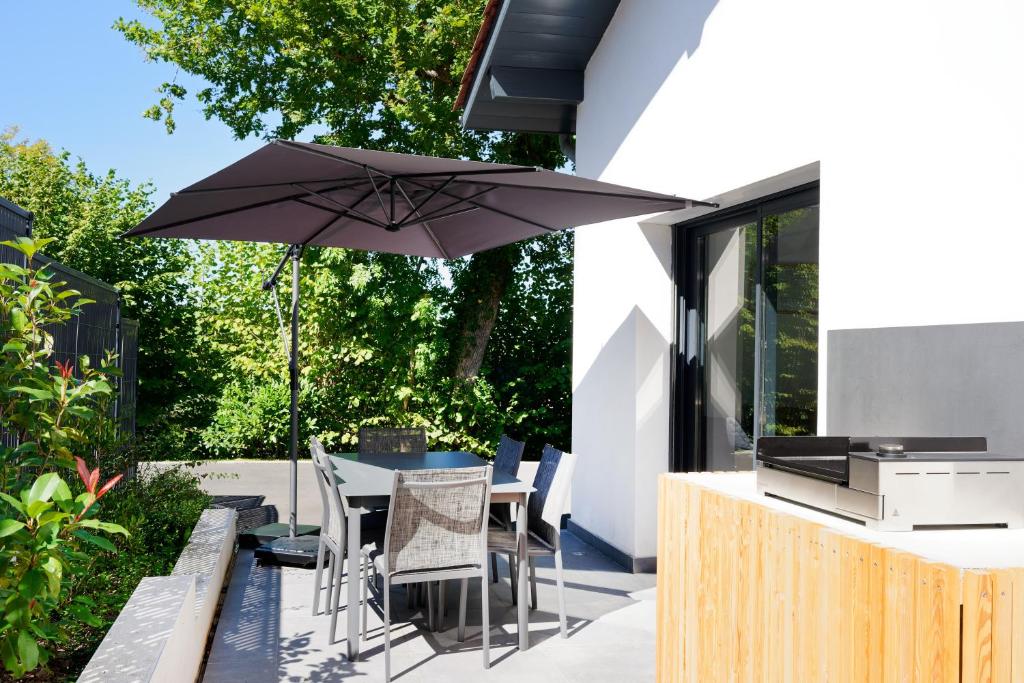 un patio con un tavolo con un ombrellone di Maison Aranea ad Ascain