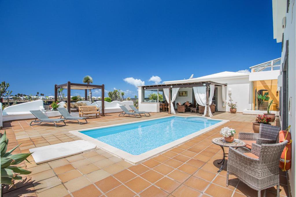 a swimming pool in a patio with chairs and a table at Villa Capricho in Lanzarote