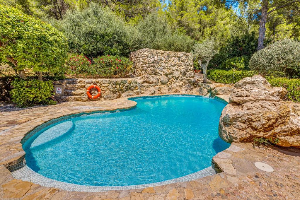 a large swimming pool with a rock wall and anergynergynergynergyploadpload at Son del Rio Vell in Pollença
