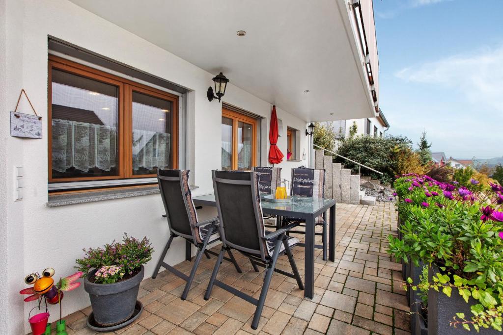a patio with a table and chairs and flowers at Haus Morgensonne in Weilheim