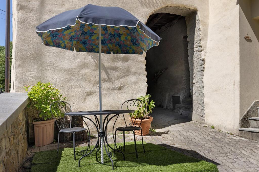 ein Tisch und Stühle mit einem Sonnenschirm in einem Innenhof in der Unterkunft Pocket House in Osiglia