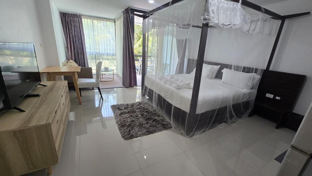 a bedroom with a canopy bed and a living room at joyful the Kris202 in Ban Lum Fuang