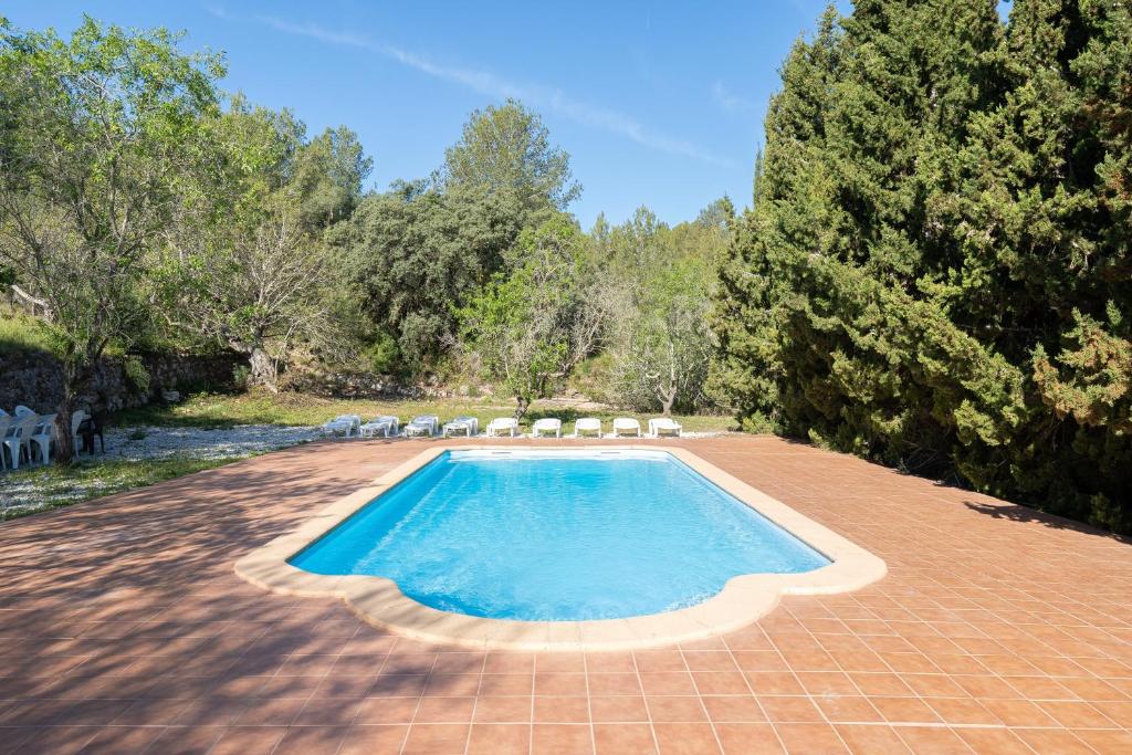 a swimming pool with chairs and trees in a yard at La Xaconera in Catllar